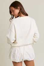 Load image into Gallery viewer, Woman wearing a white oversized sweater and shorts set on a plain background
