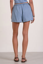 Load image into Gallery viewer, Person wearing light blue denim shorts on a plain background
