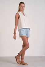 Load image into Gallery viewer, Woman wearing a white sleeveless top and light blue shorts on a plain background

