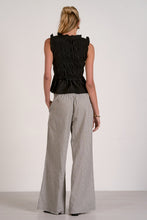 Load image into Gallery viewer, Woman wearing a black sleeveless top and checkered pants on a white background
