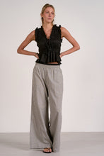 Load image into Gallery viewer, Woman wearing a black sleeveless top and checkered pants on a white background
