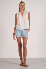 Load image into Gallery viewer, Woman wearing a white sleeveless top and light blue shorts on a plain background
