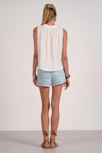 Load image into Gallery viewer, Woman wearing a white sleeveless top and light blue shorts on a plain background
