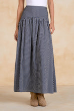 Load image into Gallery viewer, Person wearing a long black and white striped skirt on a beige background

