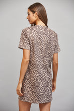 Load image into Gallery viewer, A woman shown from the back wearing a short-sleeve dress with a brown and beige zebra print, photographed against a solid light gray studio background.
