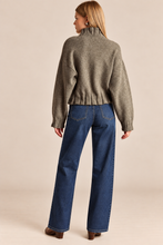 Load image into Gallery viewer, A woman shown from the back wearing a cropped, long-sleeve knit sweater in a heathered taupe-gray color and wide-leg blue jeans, standing against a solid beige studio background.
