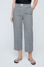 Load image into Gallery viewer, Person wearing black and white checkered pants on a plain background. Capri length.
