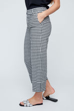 Load image into Gallery viewer, Person wearing black and white checkered pants on a plain background. Capri length.
