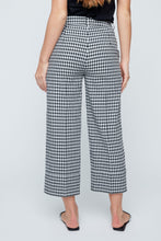 Load image into Gallery viewer, Person wearing black and white checkered pants on a plain background. Capri length.
