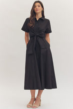 Load image into Gallery viewer, Woman wearing a midi length black dress with a bow at waistband on a white background.
