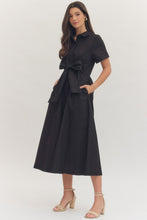 Load image into Gallery viewer, Woman wearing a midi length black dress with a bow at waistband on a white background.
