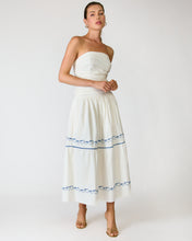 Load image into Gallery viewer, Woman wearing a white strapless dress with blue embroidery on a plain background
