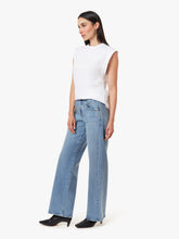 Load image into Gallery viewer, Model wearing a white sleeveless stop on a white background with straight legged blue jeans on.
